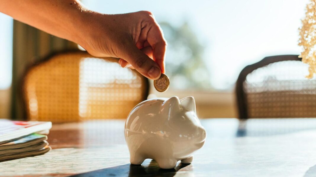 ‘It could cost me £10k but I need the money now’: Why Gen Z are opting out of pensions A hand puts pound coin into a white piggy bank.