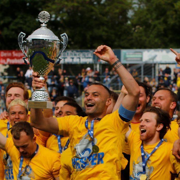Lokomotive Leipzig players celebrate and hold up their trophy