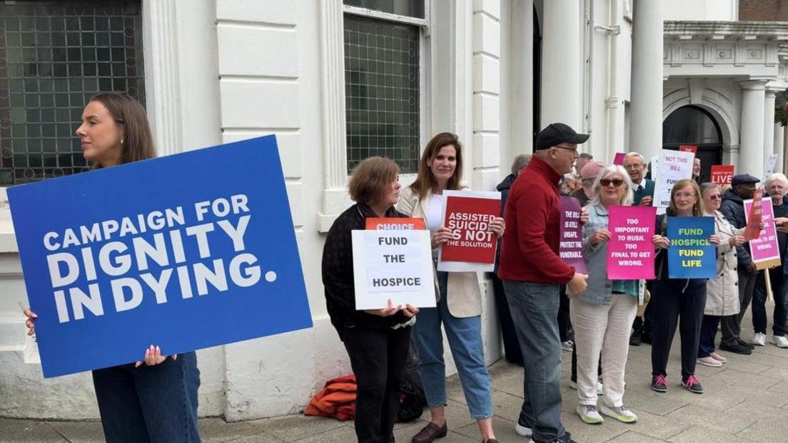 Campaigners with placards for and against the Assisted Dying Bill gather outside the Isle of Man's white parliament building.