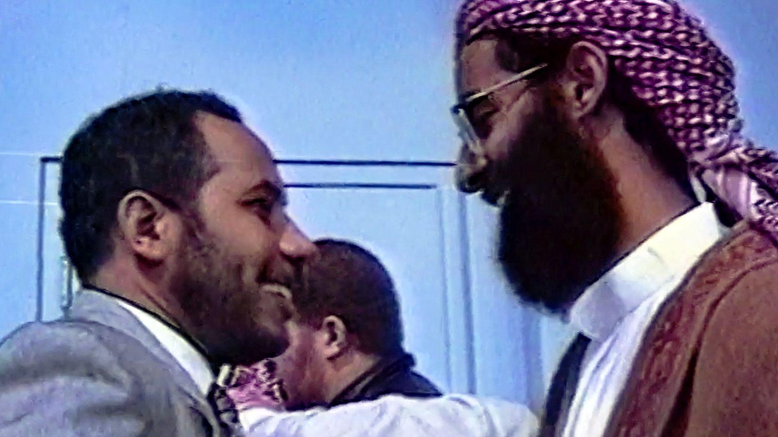 Two smiling men look at each other and are about to embrace.