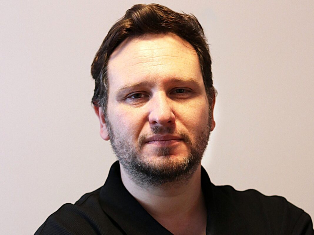 Two-week half terms: The school holiday no one can agree on A photo of a man with brown hair and stubble looking straight into the camera. He is wearing a black top.