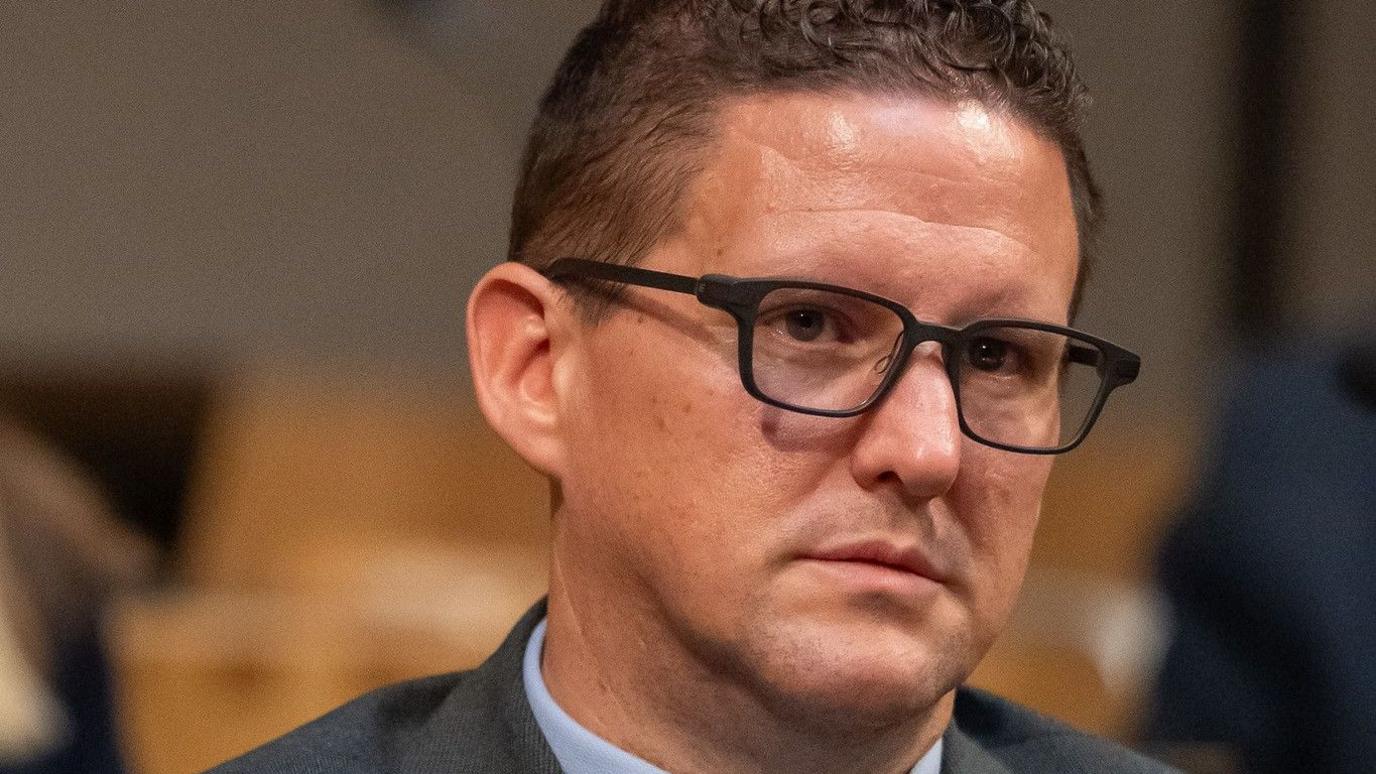 Jason O'Connell wearing black rimmed glasses and sat in the Senedd