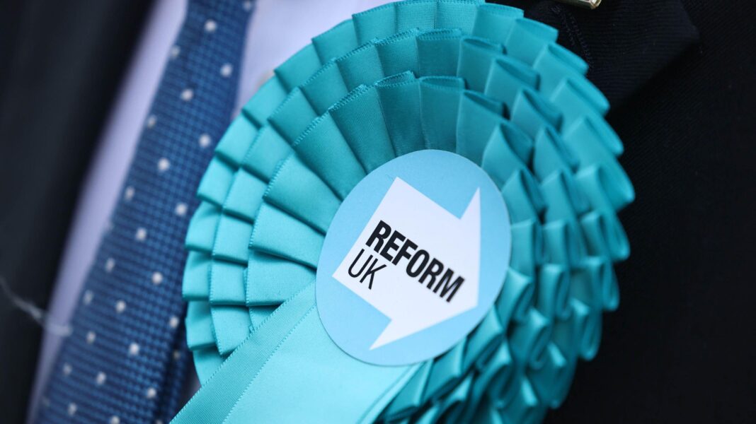 Reform faces questions over candidate vetting after undercover filming A light blue Reform UK rosette pinned on a person wearing a suit and a dark blue tie.