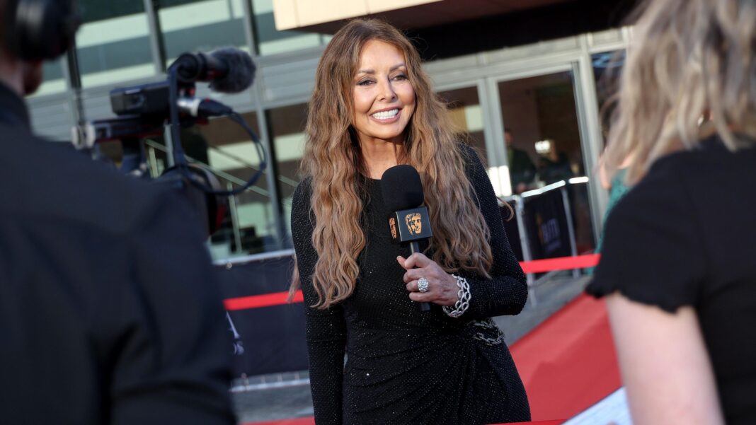 Carol Vorderman wearing a black dress smiling holding a microphone