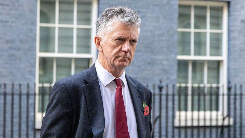 Jonathan Powell outside 10 Downing Street wearing a suit and tie.
