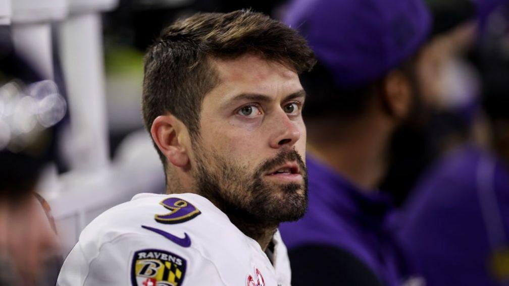 Head and shoulders of Justin Tucker, wearing a white top, short dark hair, and dark beard