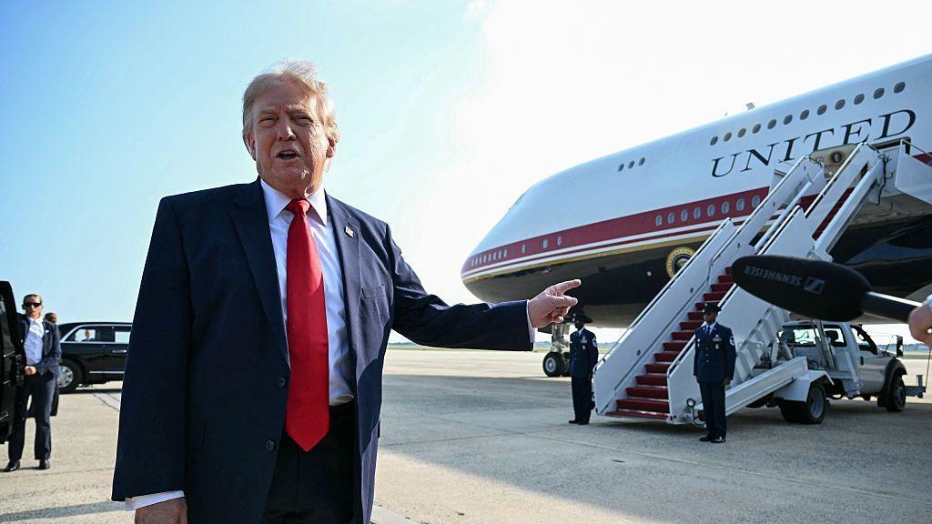 US President Donald Trump on an airport tarmac pointing to the Qatari-gifted aircraft that has served as Air Force One