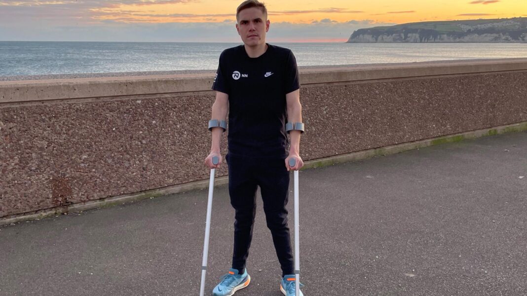 Jake Smith standing near the sea and using crutches