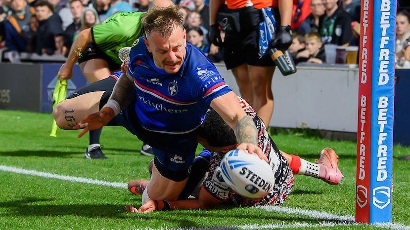Wakefield winger Tom Johnstone makes a one-handed dive for the line with Leigh's Umyla Hanley desperately trying to drag him into touch