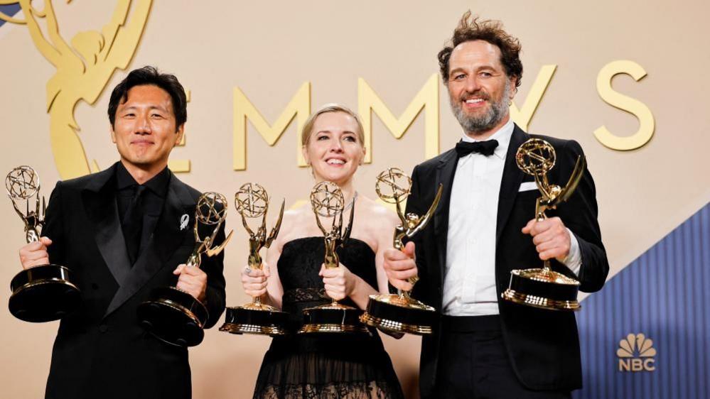 Hiro Murai, Katie Dippold and Matthew Rhys are all holding Emmy Awards in both hands.