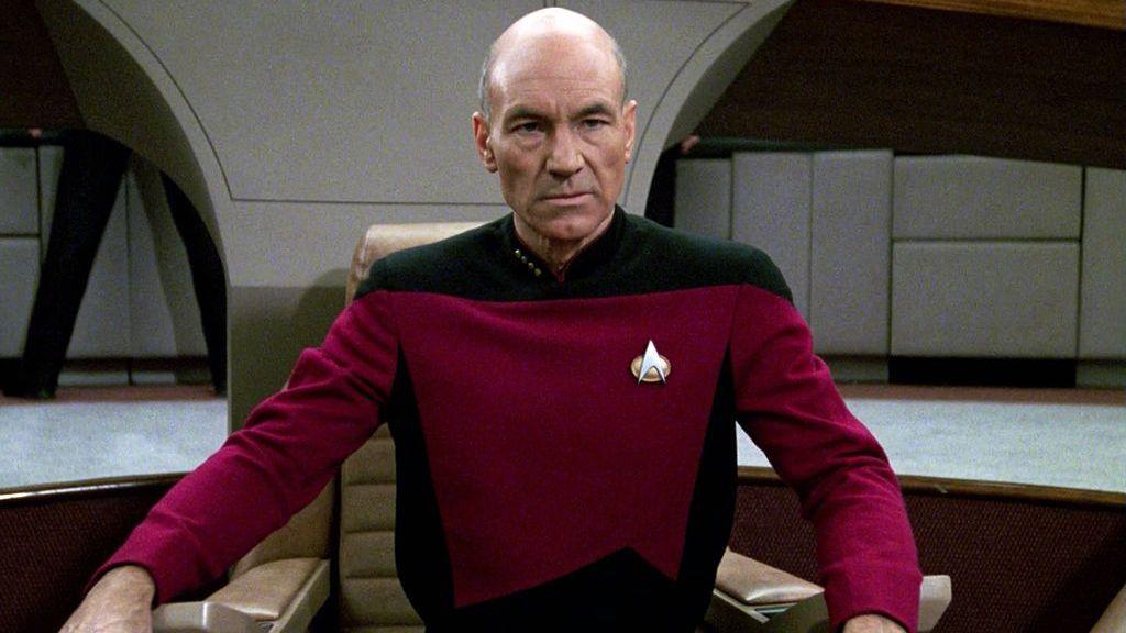 Sir Patrick Stewart seen playing Captain Jean-Luc Picard. He is wearing a red and black Star Trek uniform
