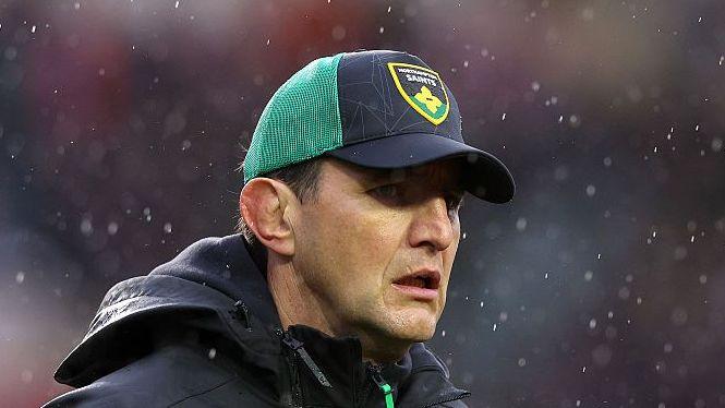 Northampton Saints director of rugby Phil Dowson wearing a black and green Northampton Saints cap looking on in the rain prior to his side's match against Leicester Tigers.