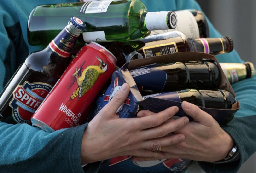 ‘That nagging feeling of dread’: Is ‘hang-xiety’ a real thing? A picture of a man struggling to carry several types of alcohol bottles - including various beers as well as red wine and gin. The man, whose face we cannot see, is wearing a light blue jumper.