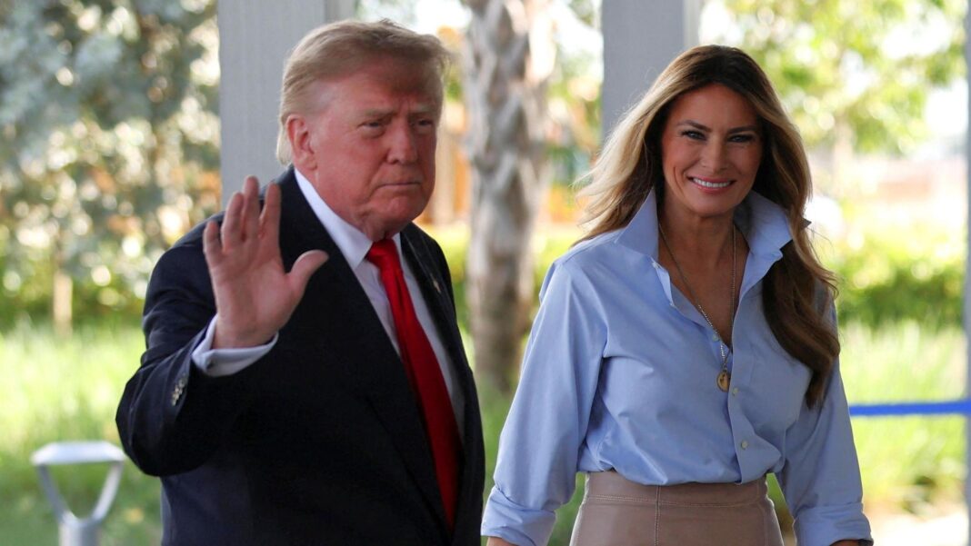 Donald Trump waves as he walks next to a smiling Melania Trump