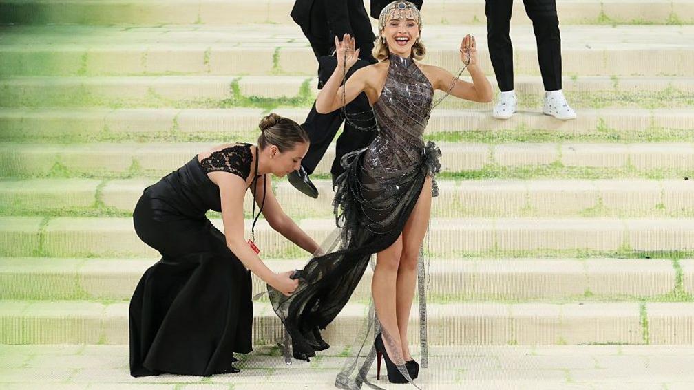 An assistant adjusts Sabrina Carpenter's dress at the Met Ball in New York in May