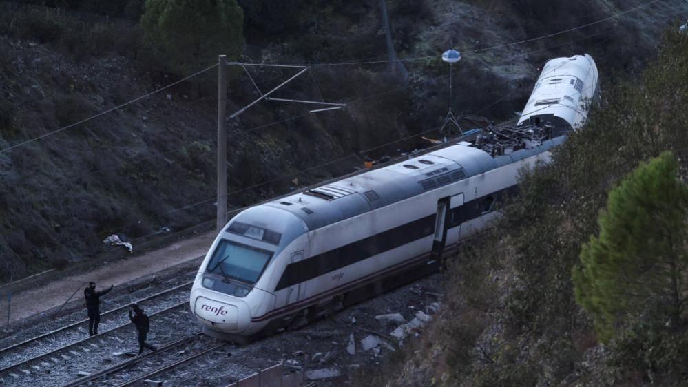 Members of the Spanish Civil Guard work next to one of the trains involved in the accident