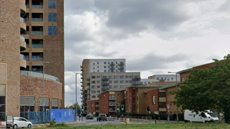 St Paul's Road, near a grass covered roundabout. There are several high rise buildings on both sides of the road, which are in red and brown brick. Cars and a van are seen travelling in and out of the road.