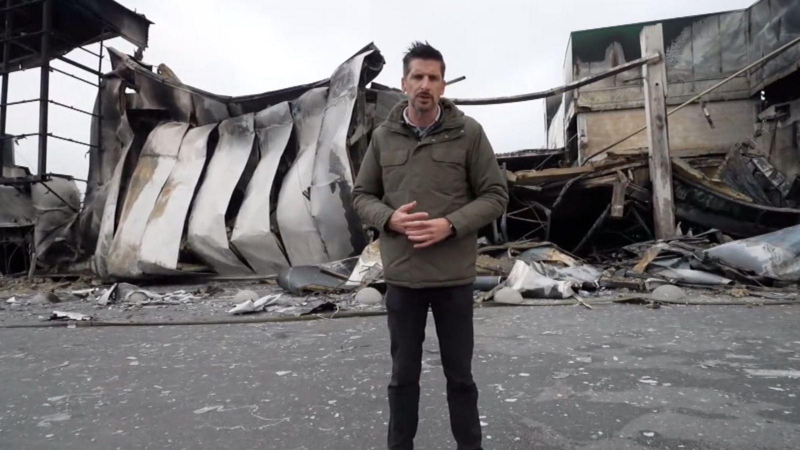 BBC Correspondent Dan Johnson stands in front of destroyed retail park