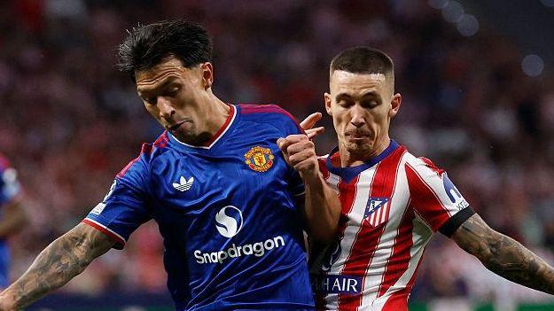 Lisandro Martinez, wearing Manchester United's blue away kit, battles for possession against Atletico Madrid