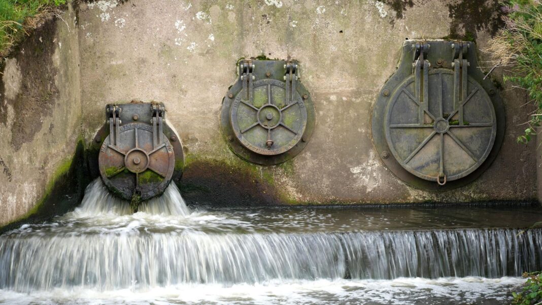 Water discharges from three outlet pipes of varying sizes, below is a step of water cascading down
