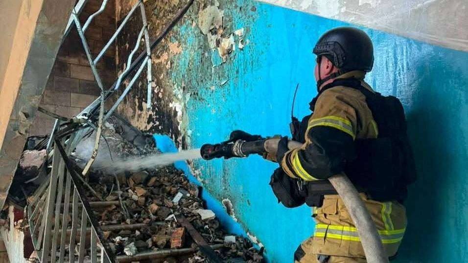 A firefighter pours water on the rubble on a staircase