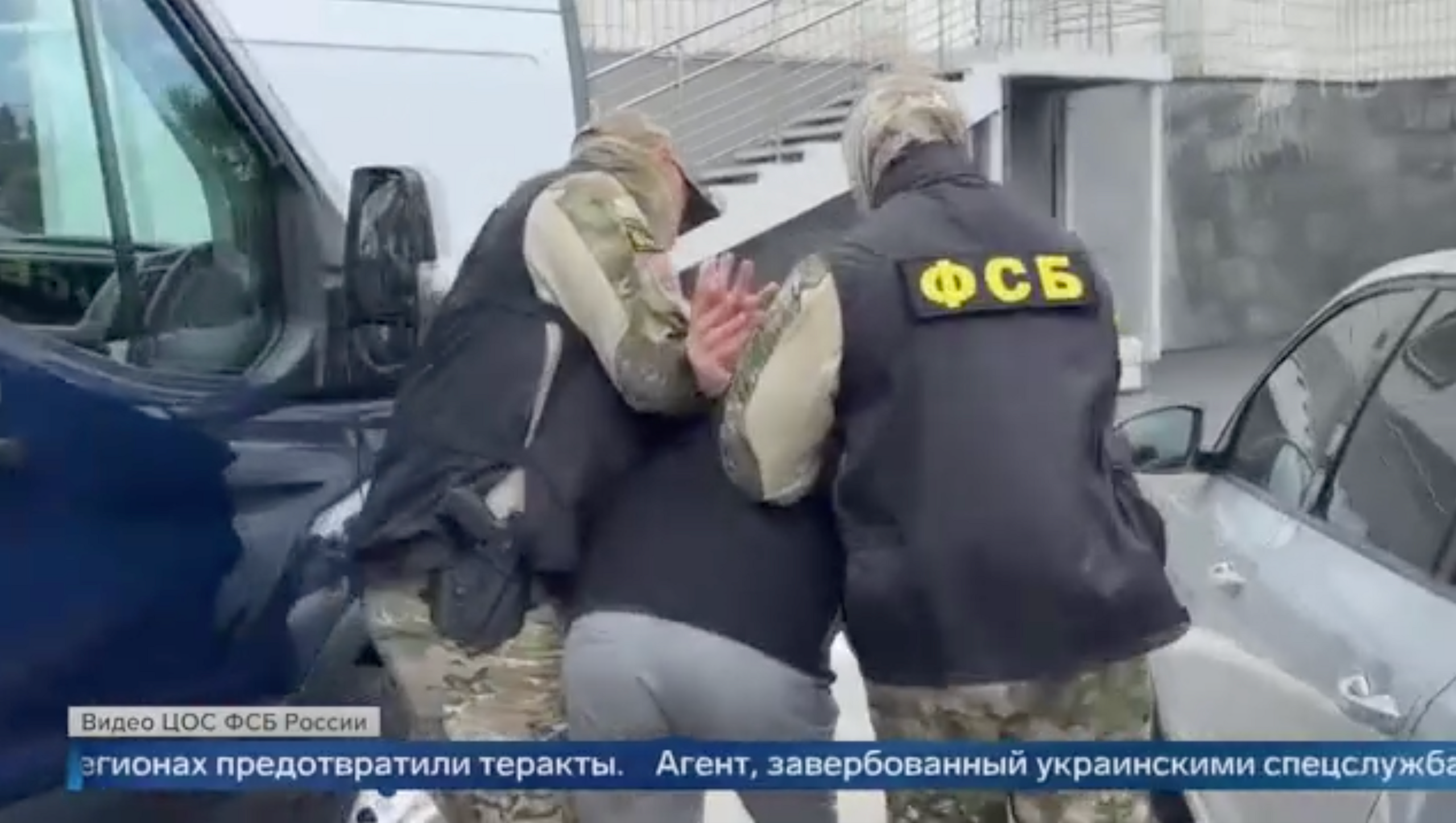 A man is retrained and placed in handcuffs by two FSB officers. The footage is being shown on Russian television
