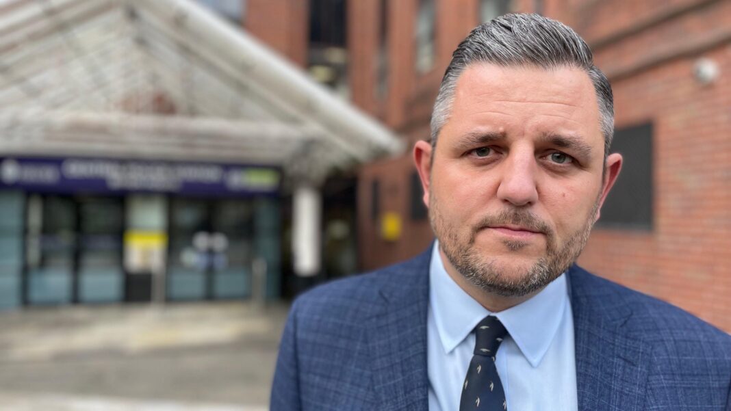 Four arrested after police officer injured in shooting A man with short grey hair and a beard wearing a blue suit jacket and light blue shirt stood outside a building