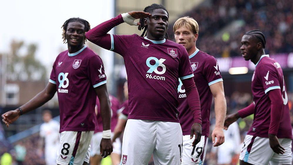 Loum Tchaouna of Burnley gives a salute to fans after scoring against Leeds wearing a claret match shirt and white shorts