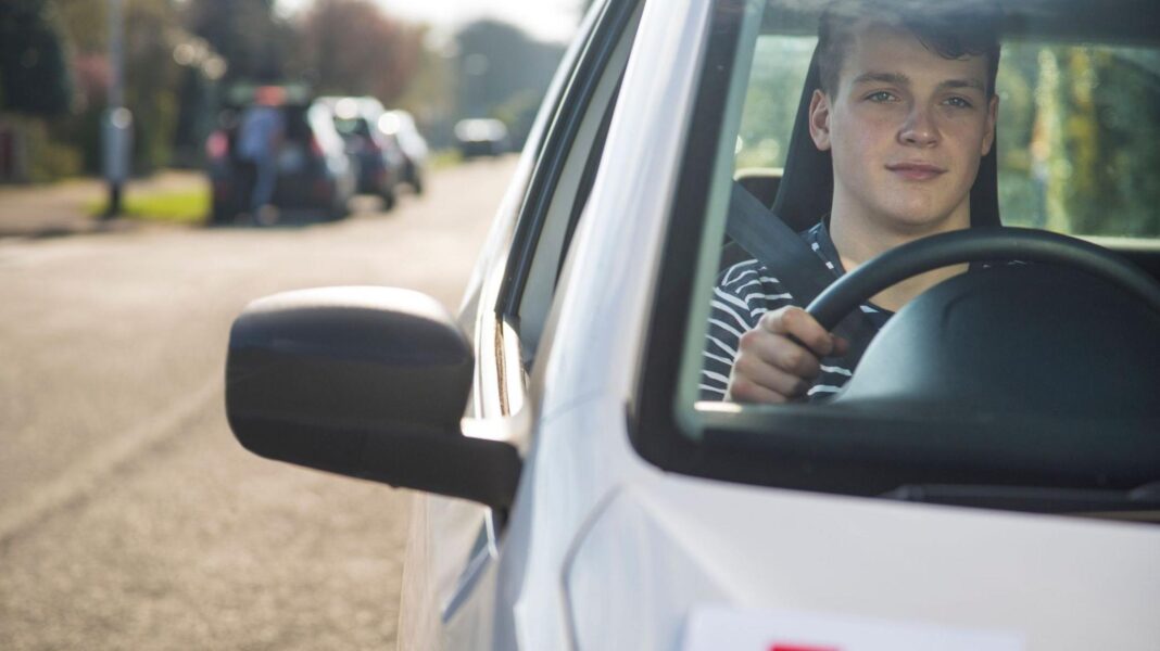 A learner driver in a silver car wearing a black and white stripy top.