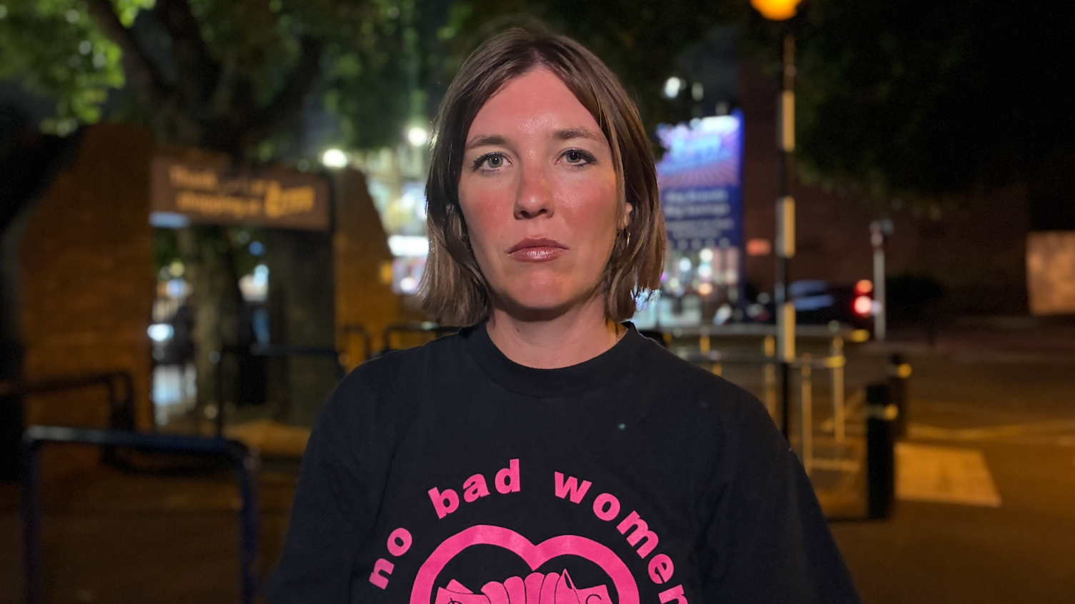 Laura Watson, a caseworker from the English Collective of Prostitutes with shoulder-length brown hair, wears a black and pink sweatshirt that reads: no bad women