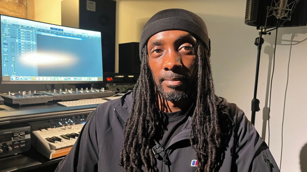 How West Midlands shed its gun crime capital label Zimbo is wearing a black hat and has long dreadlocks and a black jacket. Behind him is a computer screen and recording equipment.