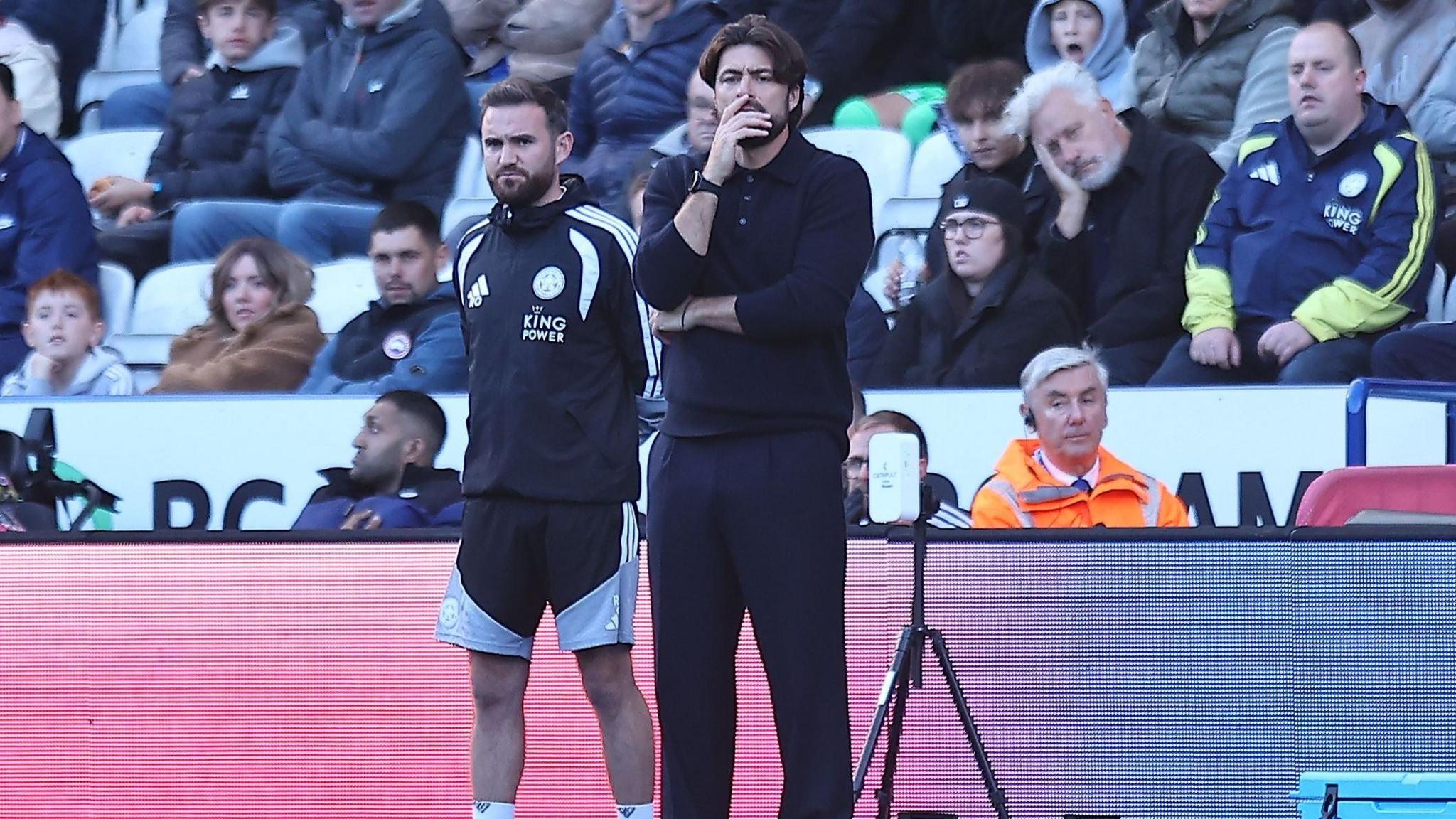 Russell Martin looks deep in thought on the touchline with scores of disappointed fans in the seats behind him