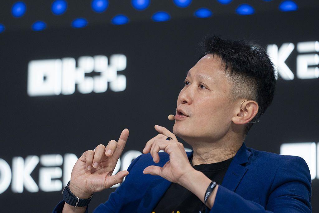 A close up of Binance co-chief executive officer Richard Teng in a blue jacket and black t shirt speaking at a conference.