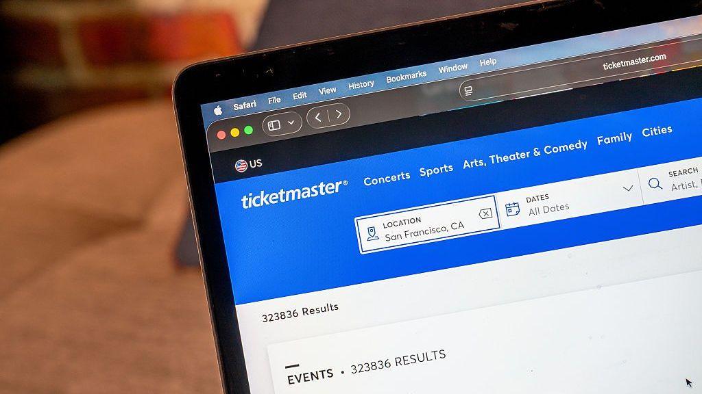 Ticketmaster's website is displayed on a MacBook screen, showing the site's search boxes where users can find events or concerns by location, date or artist.