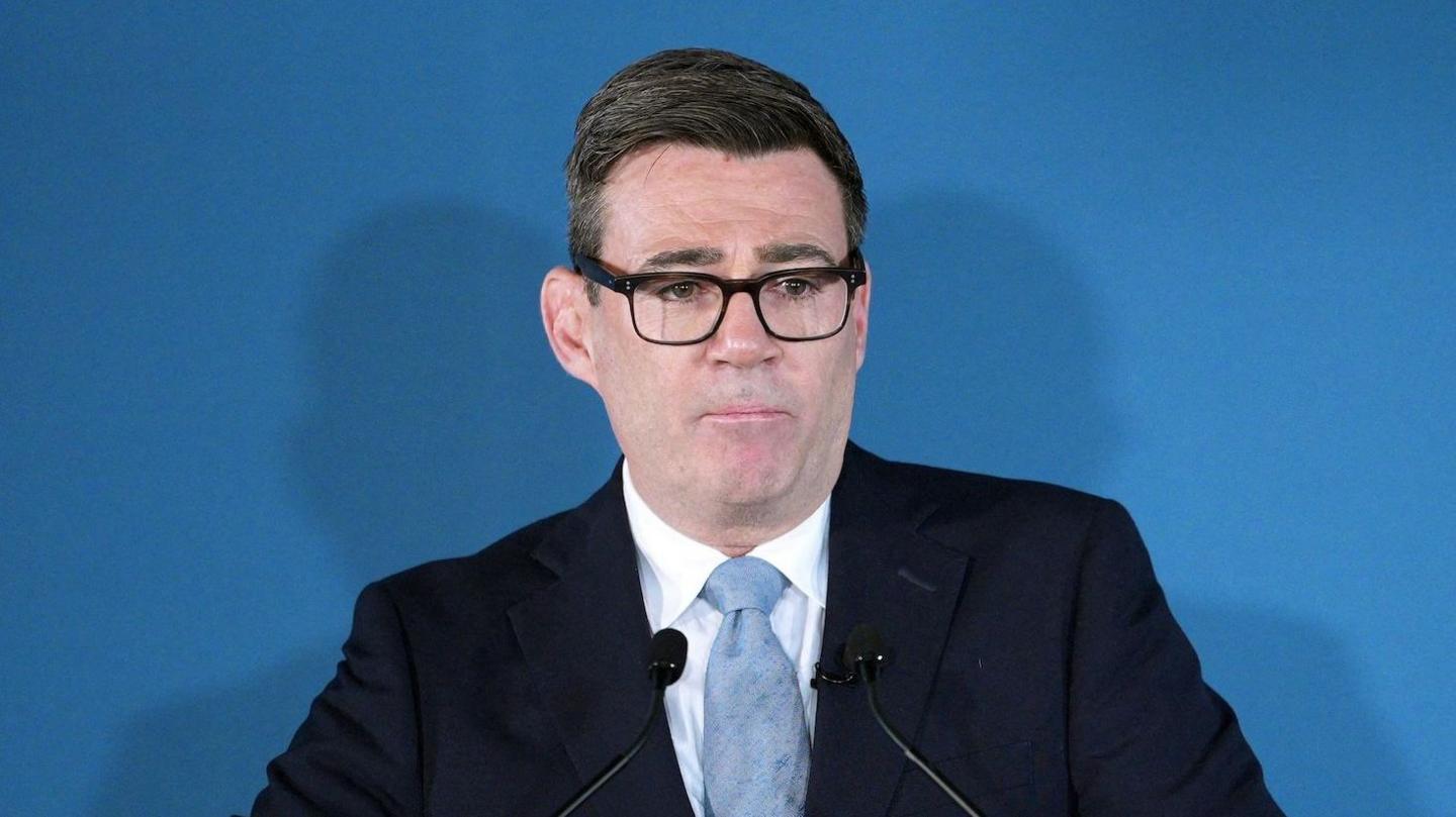 Prime Minister Andy Burnham wears a dark suit and pale blue tie as he speaks into two microphones at a podium at the Innovation Nation summit on 9 October.