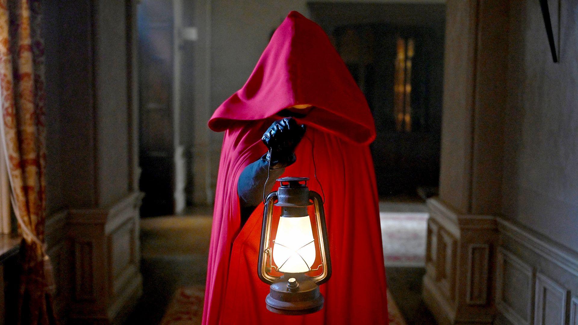 A figure in a red cloak holding a lamp
