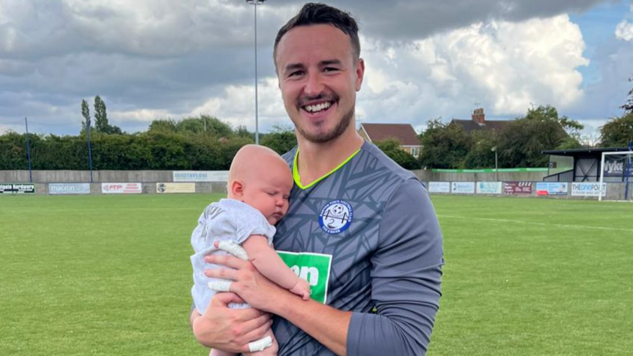 Former Barton Town goalkeeper James Hitchcock pictured with his baby son, Freddie, at a football match