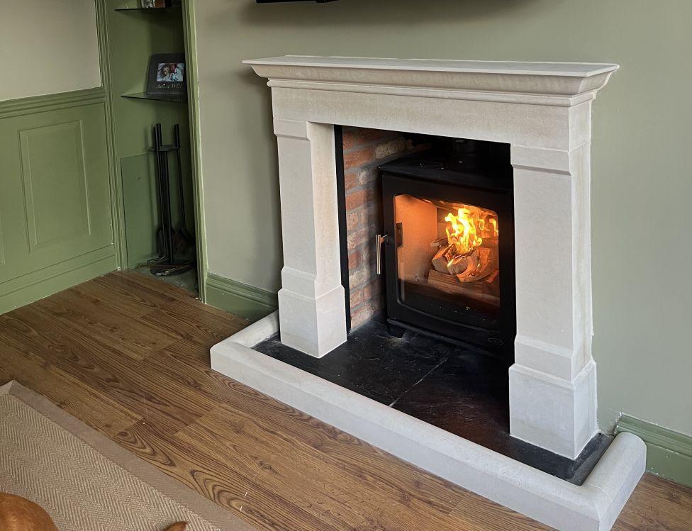 A white fireplace on a sage green painted wall
