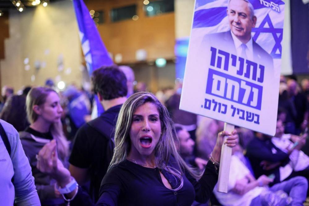A woman holds up a sign with Netanyahu's image on it.
