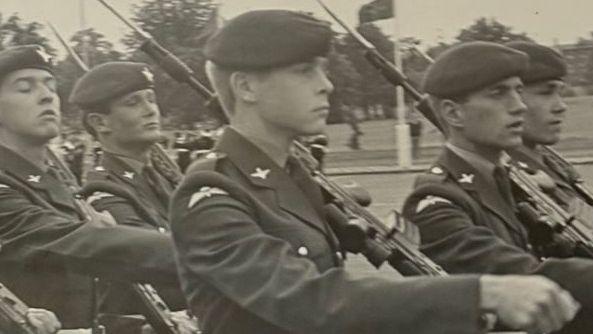 A black and white image of British paratroopers marching with rifles.