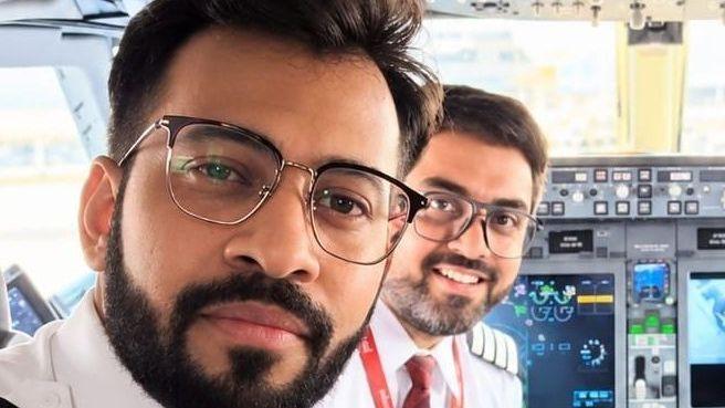 Indian pilot Smit Machchhar and his friend Captain Dharav Gosalia smiling into a camera as they sit in the cockpit of a plane.