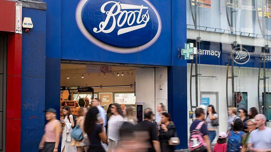 Shoppers walk by a Boots store in central London