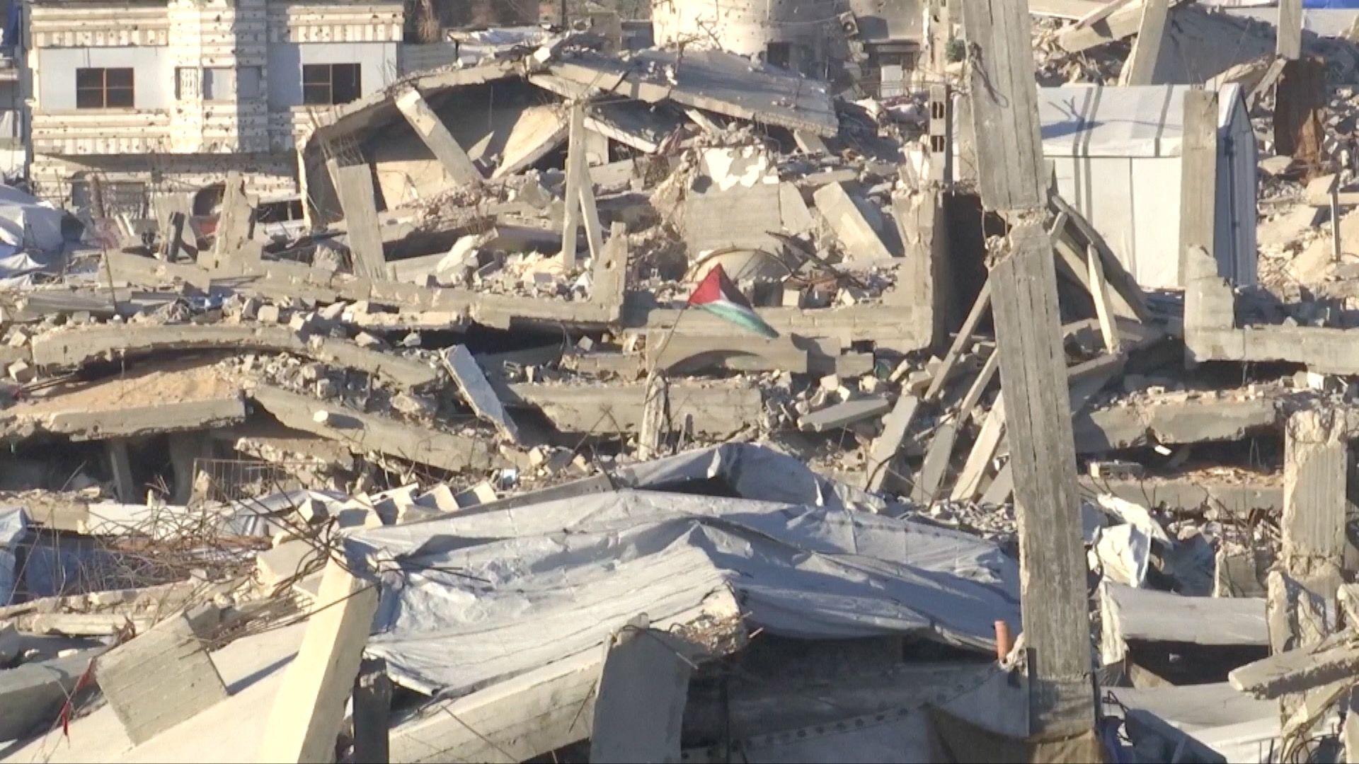A Palestinian flag flies in rubble in Gaza