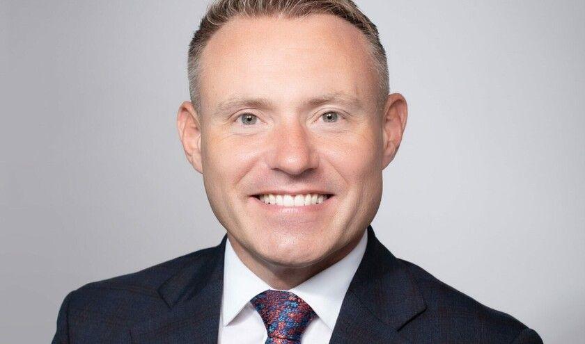 Adam Doyle dressed in a suit jacket, white shirt and tie