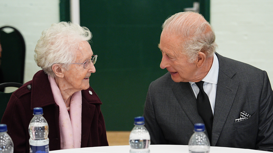 The King is sat next to and chatting to a woman.