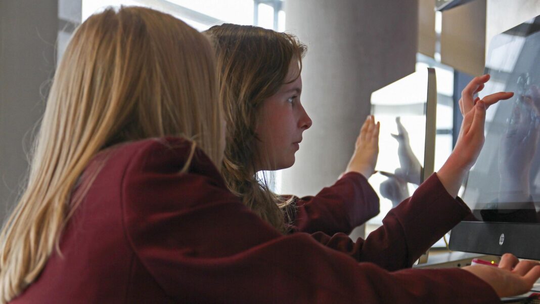 Cut screen time in classrooms to avoid long-term health issues, government urged Three students use touchscreens in a close-up. Only one girl's face is visible as she stares intently at the screen.
