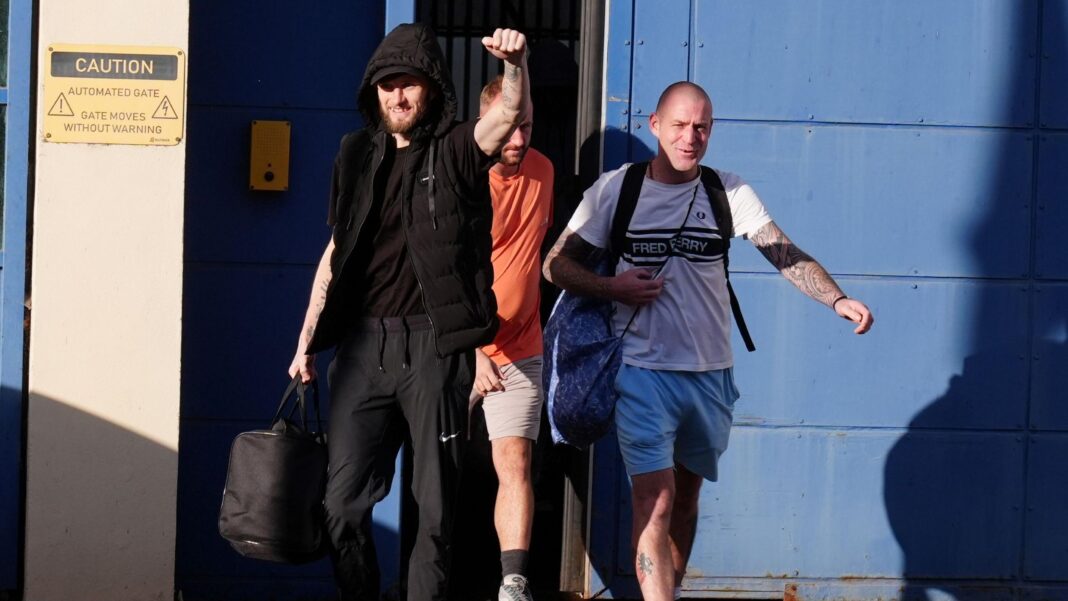 Hundreds more prisoners being freed in second phase of early release scheme Three men leaving HMP Durham in north east England on 13 October. The group of three are in bright sunshine and smiling. The man in front is bearded and all in black with his had raised in a victory punch. Behind him is a bald-headed man wearing blue shorts and a white "Fred Perry" t-shirt and behind him is a blond man wearing stone-coloured shorts and an orange t-shirt
