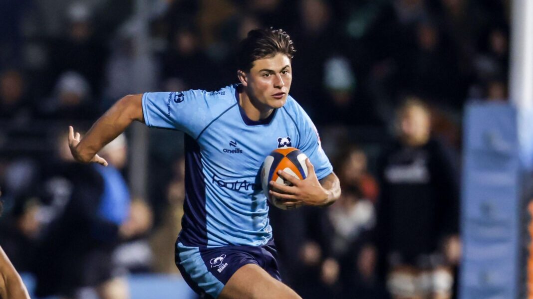 Louis Rees-Zammit runs with a rugby ball tucked to his body, wearing a light blue Bristol Bears away kit