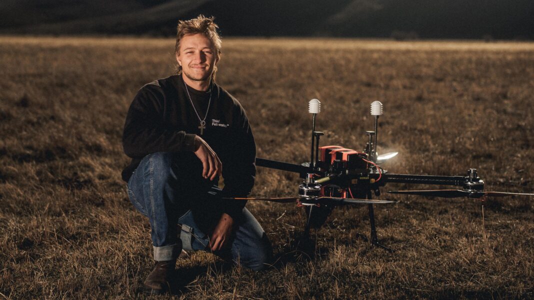 Rainmakers: The drones used to seed clouds Augustus Doricko is one one knee next to a large drone. They are in a field.