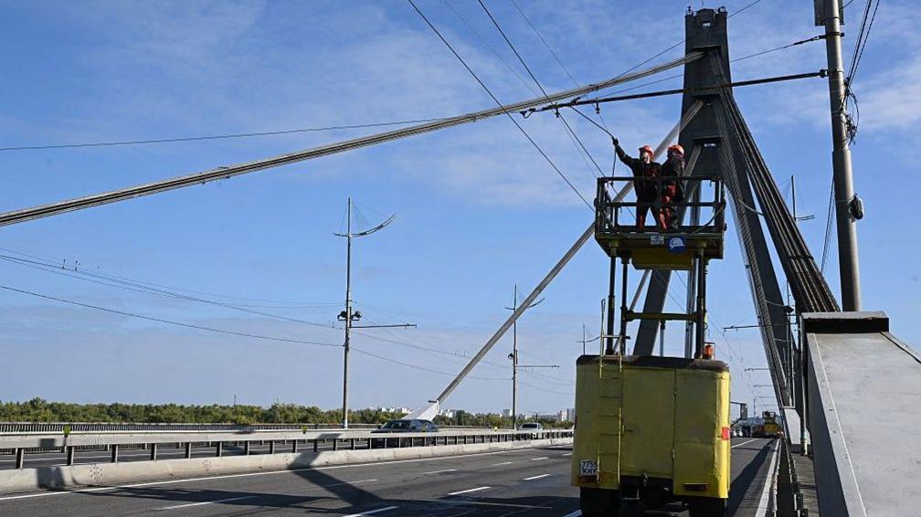 Technicians repair overhead trolleybus power lines that was damaged following an attack on the Pivnichnyi (Northern) Bridge in Kyiv, Ukraine. Photo: 3 October 2026